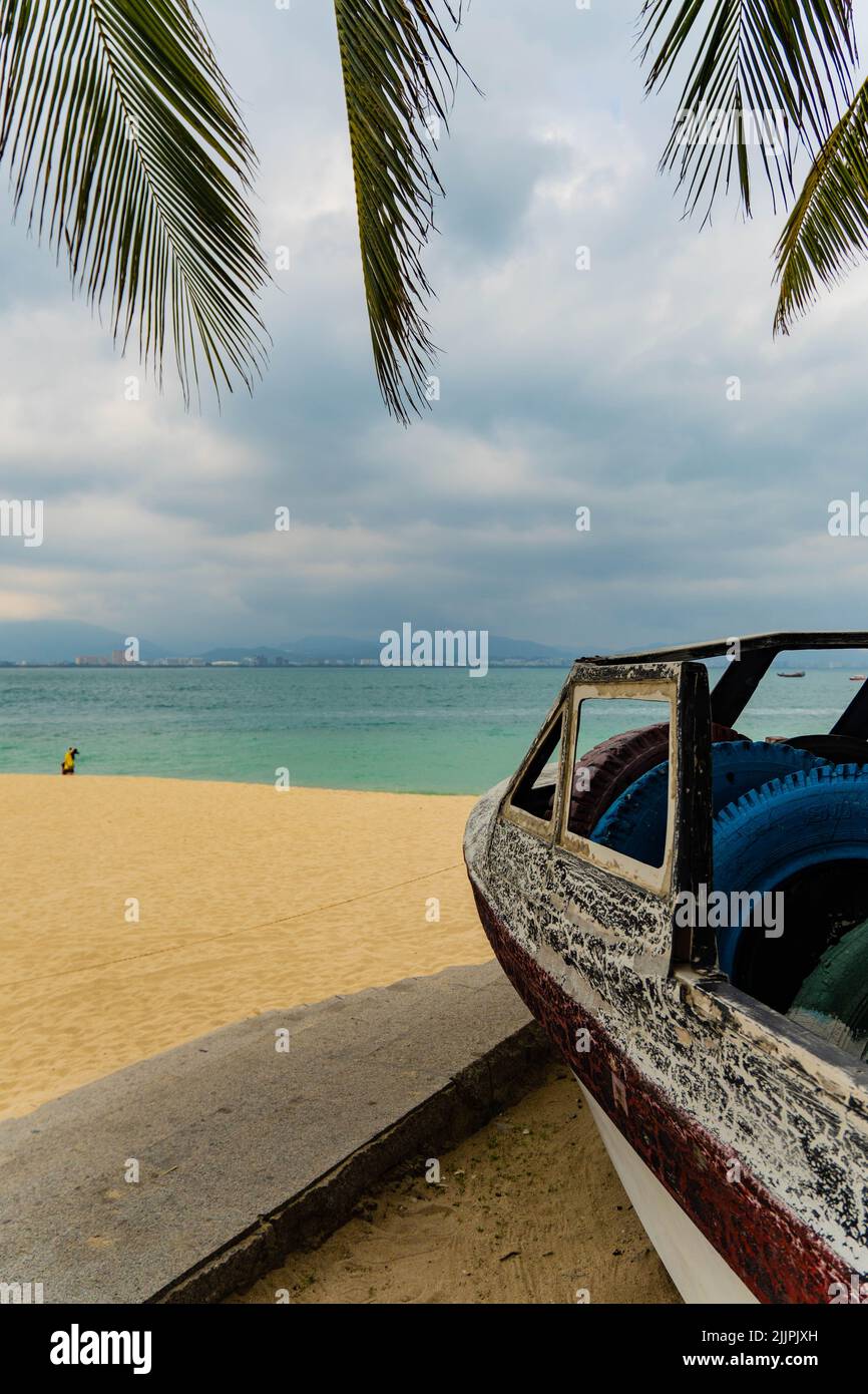 A vertical shot of a broken car parked near the beach Stock Photo