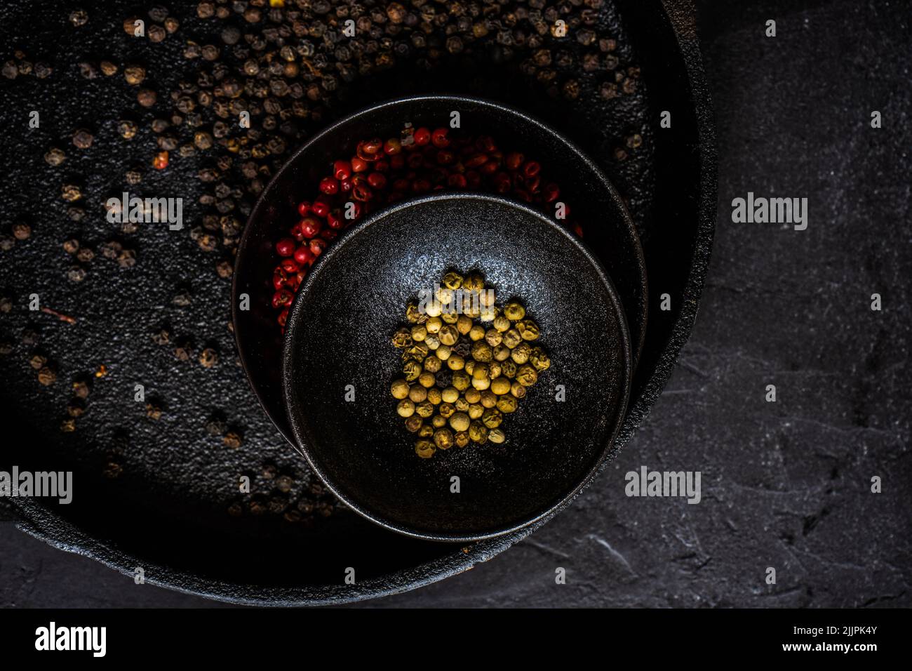 Overhead view of bowls of pink, white and black peppercorns on a table Stock Photo