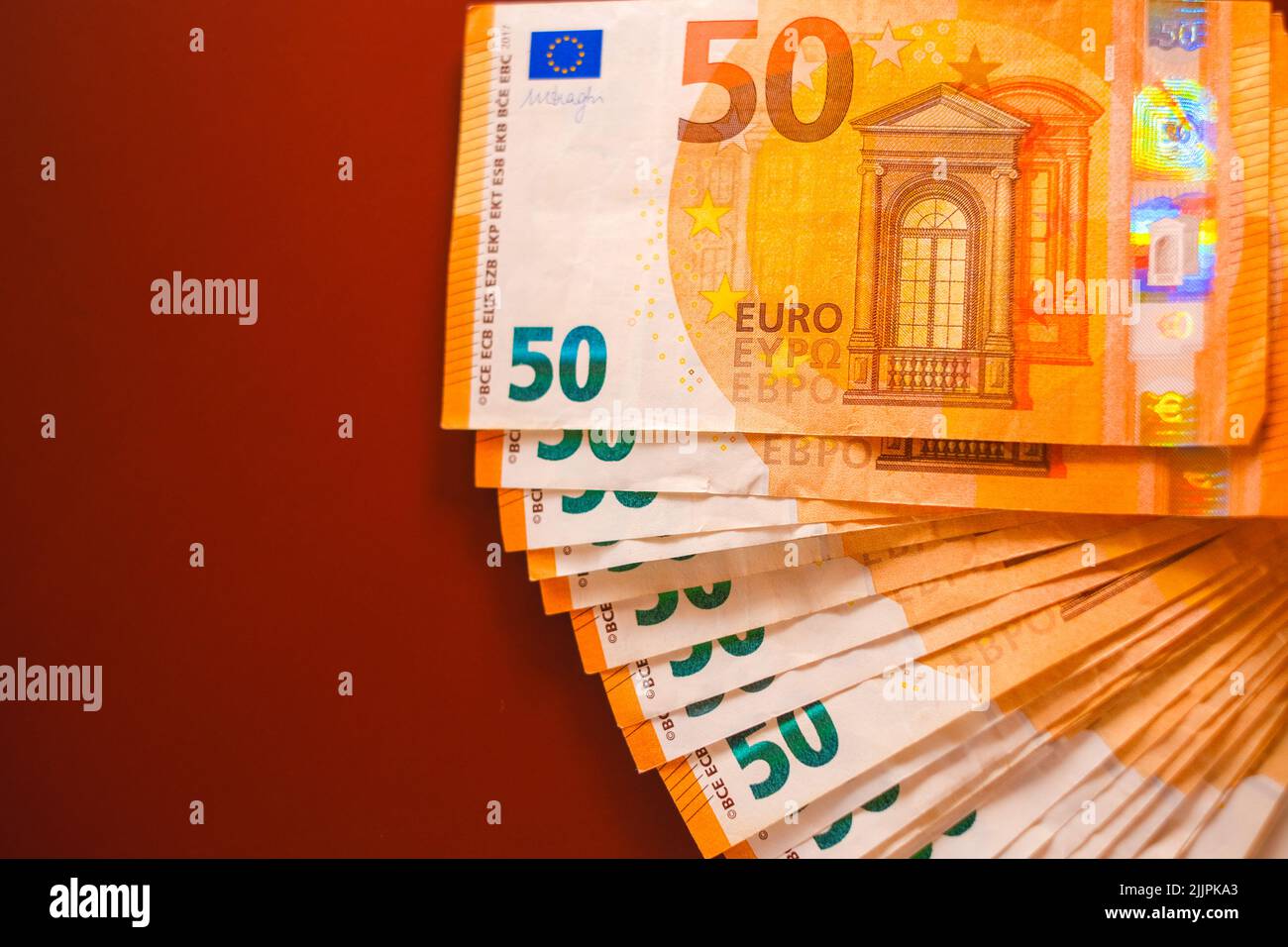 Euro money. Money background.fifty euros banknotes pack on a burgundy background.Spending and income in European countries.Income and expenses in the Stock Photo