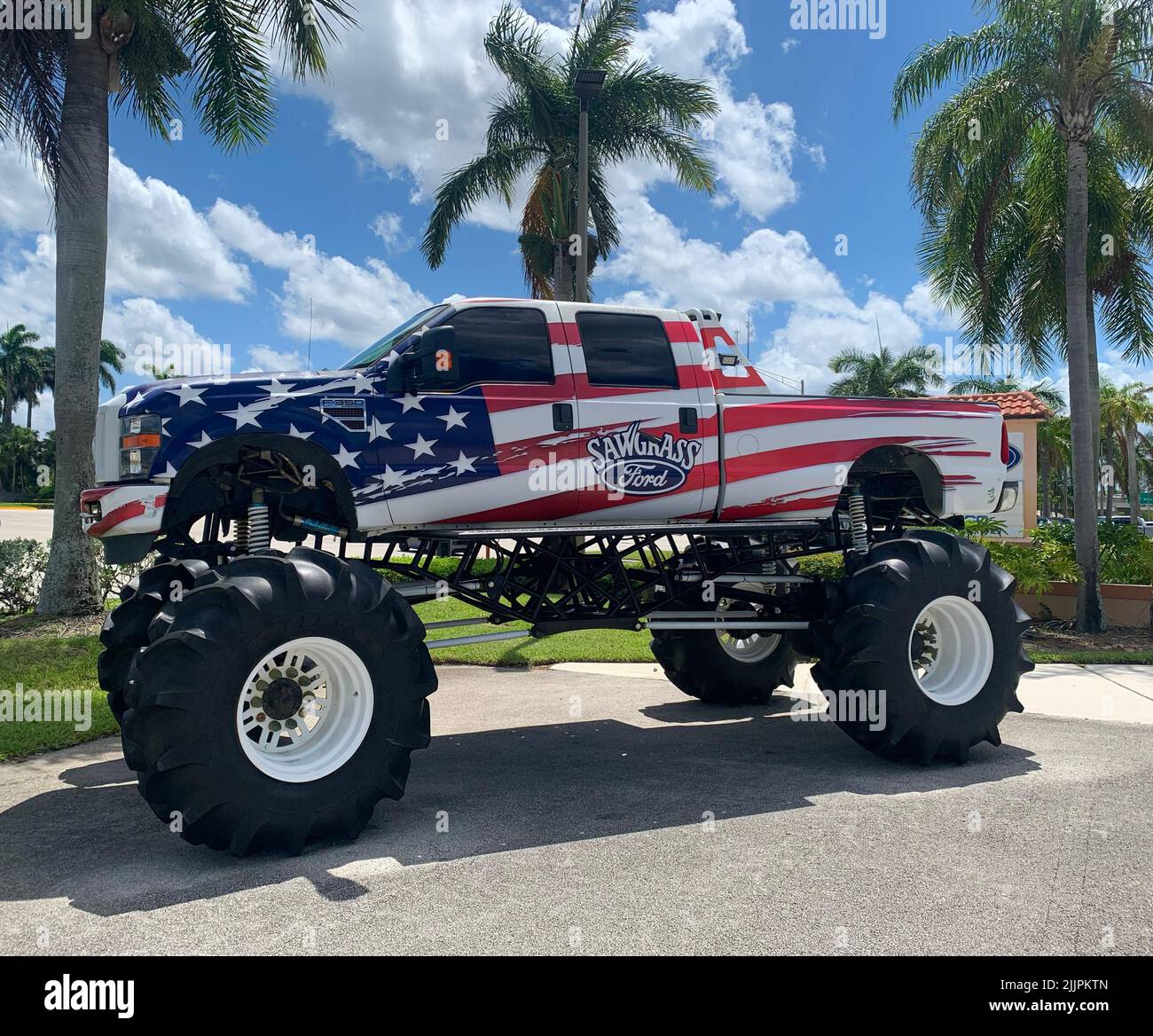 A Ford sawgrass monster truck with an American flag parked under the palms. Stock Photo