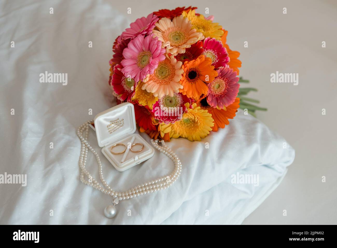 closeup shot of bouquet of colofull flowers with two rings and a necklace Stock Photo