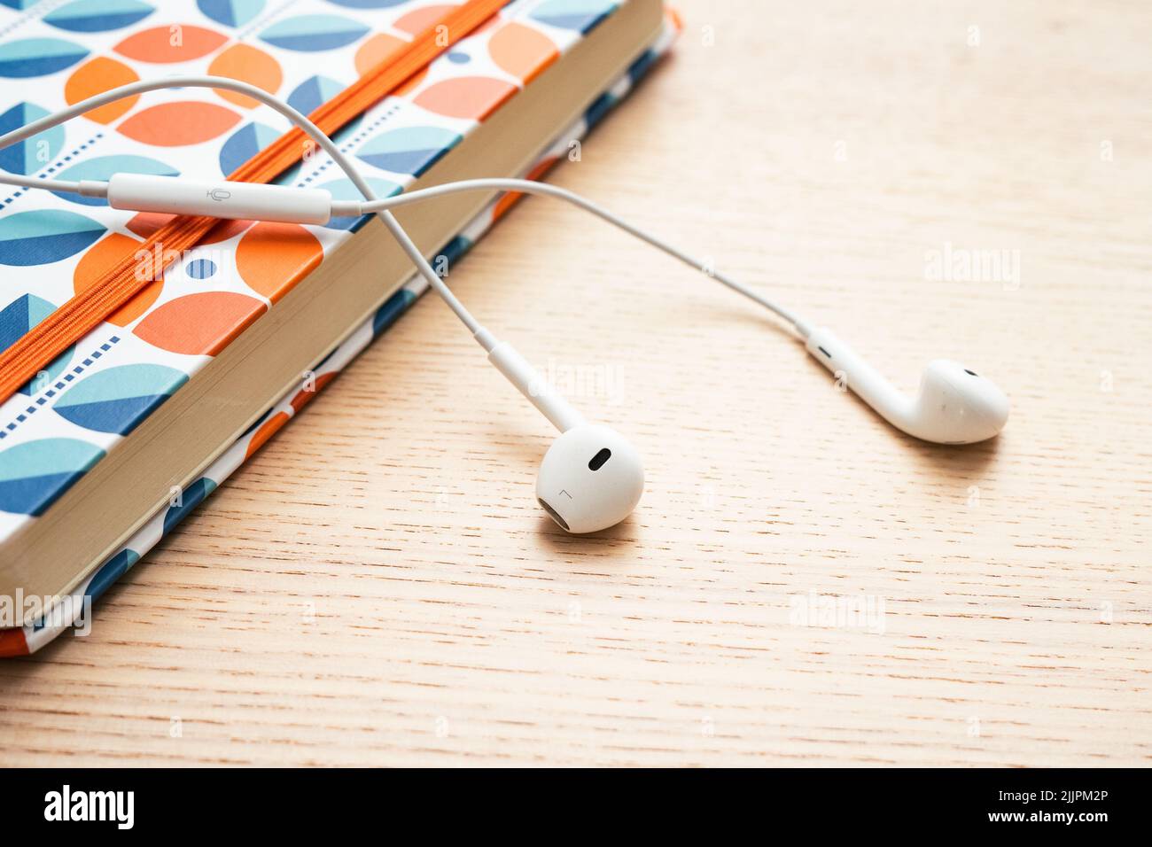 White headphones lying on the orange notebook Stock Photo