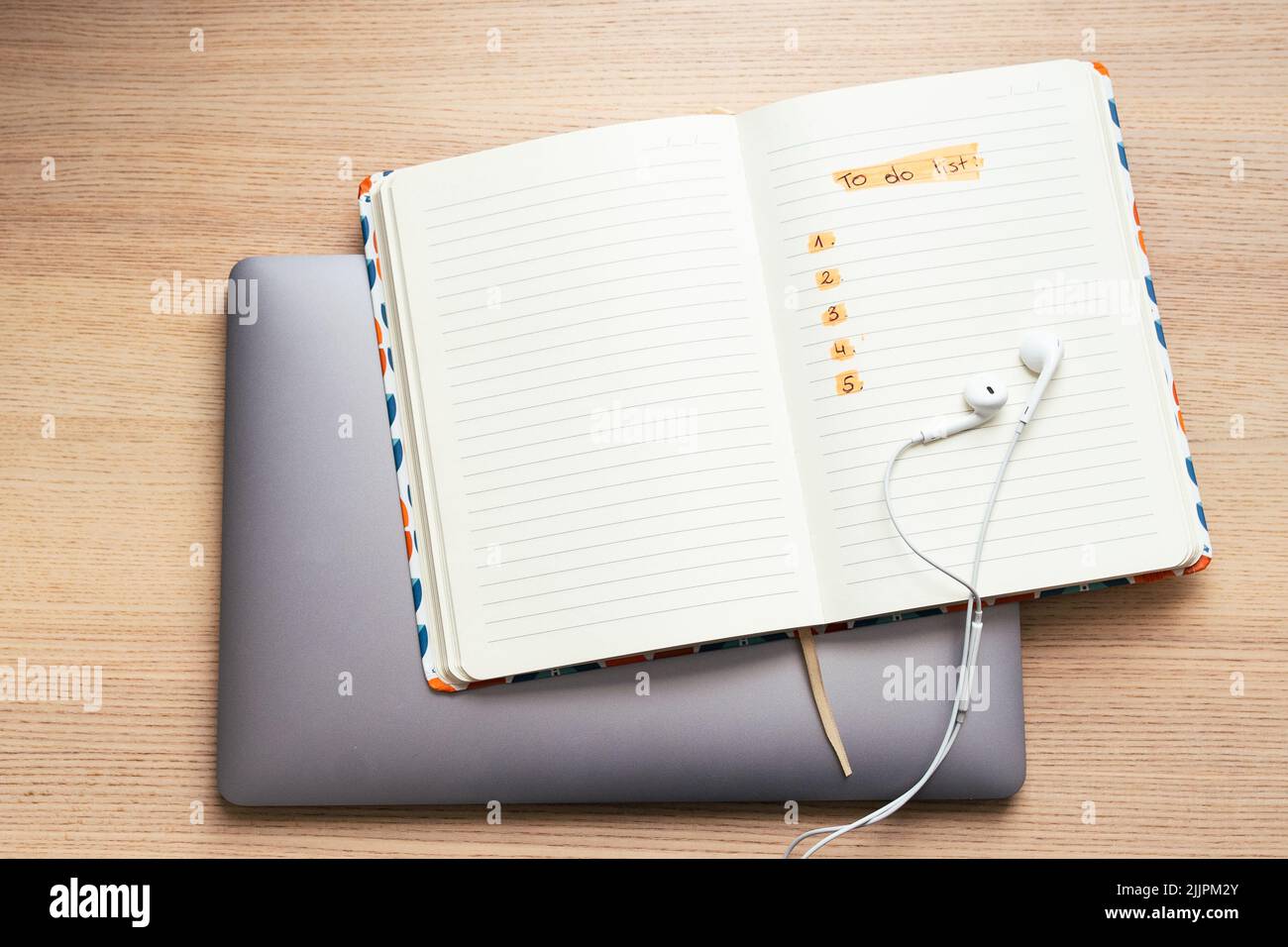 A top view of open notepad with 'to do list' text and headphones on laptop computer Stock Photo