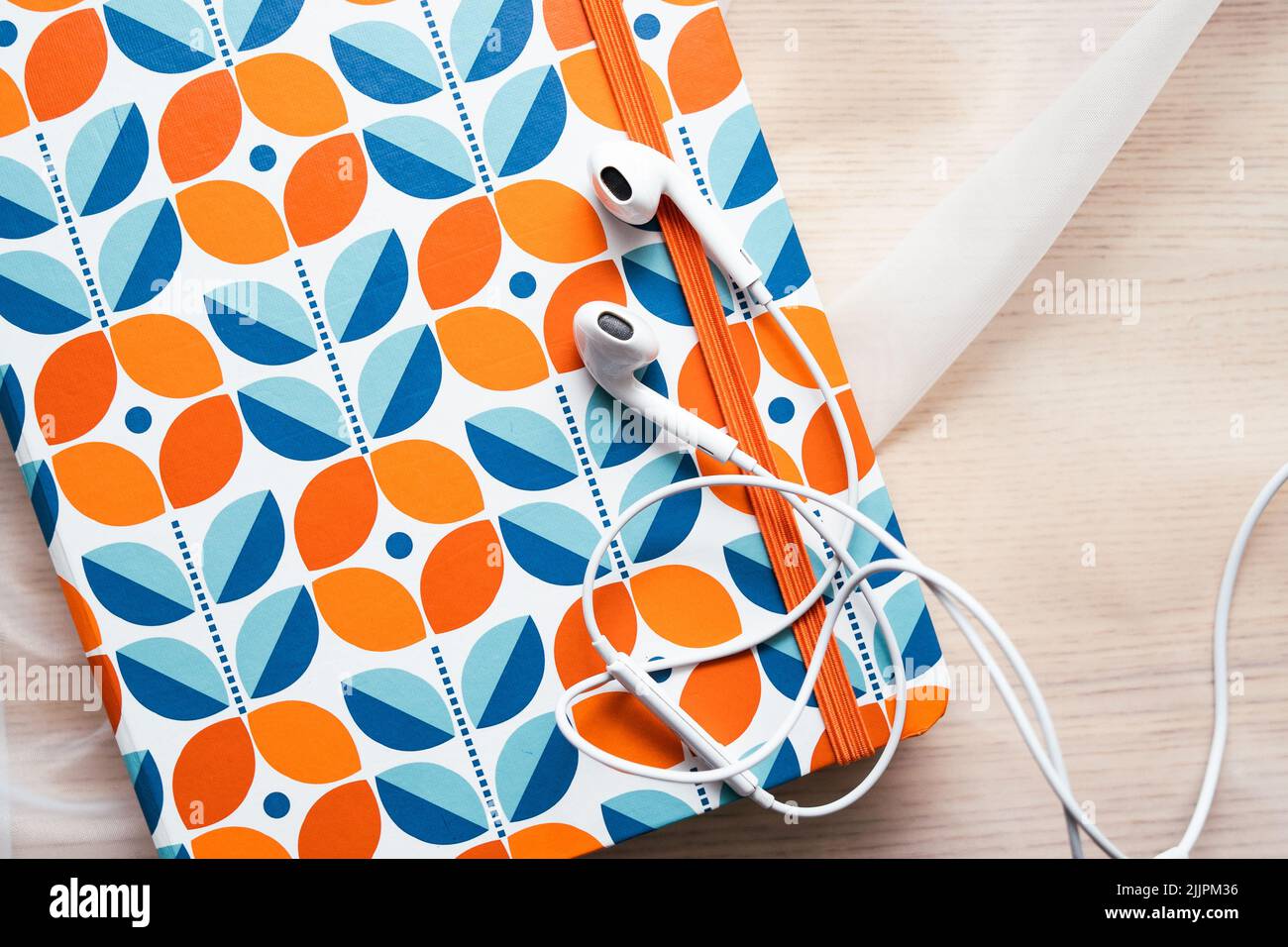 White headphones lying on the orange notebook Stock Photo