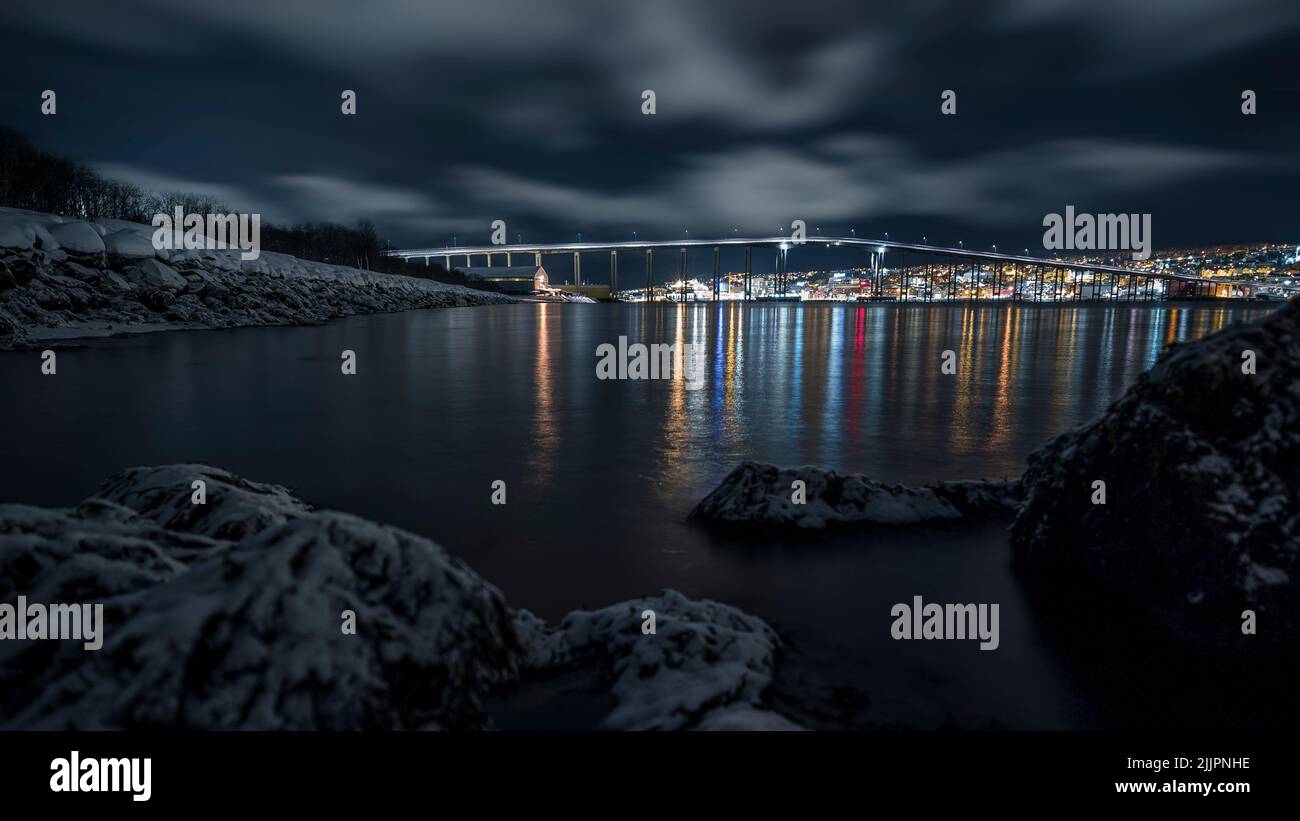 A beautiful night shot of a bridge and city reflected in water in Tromso, Norway in winter Stock Photo