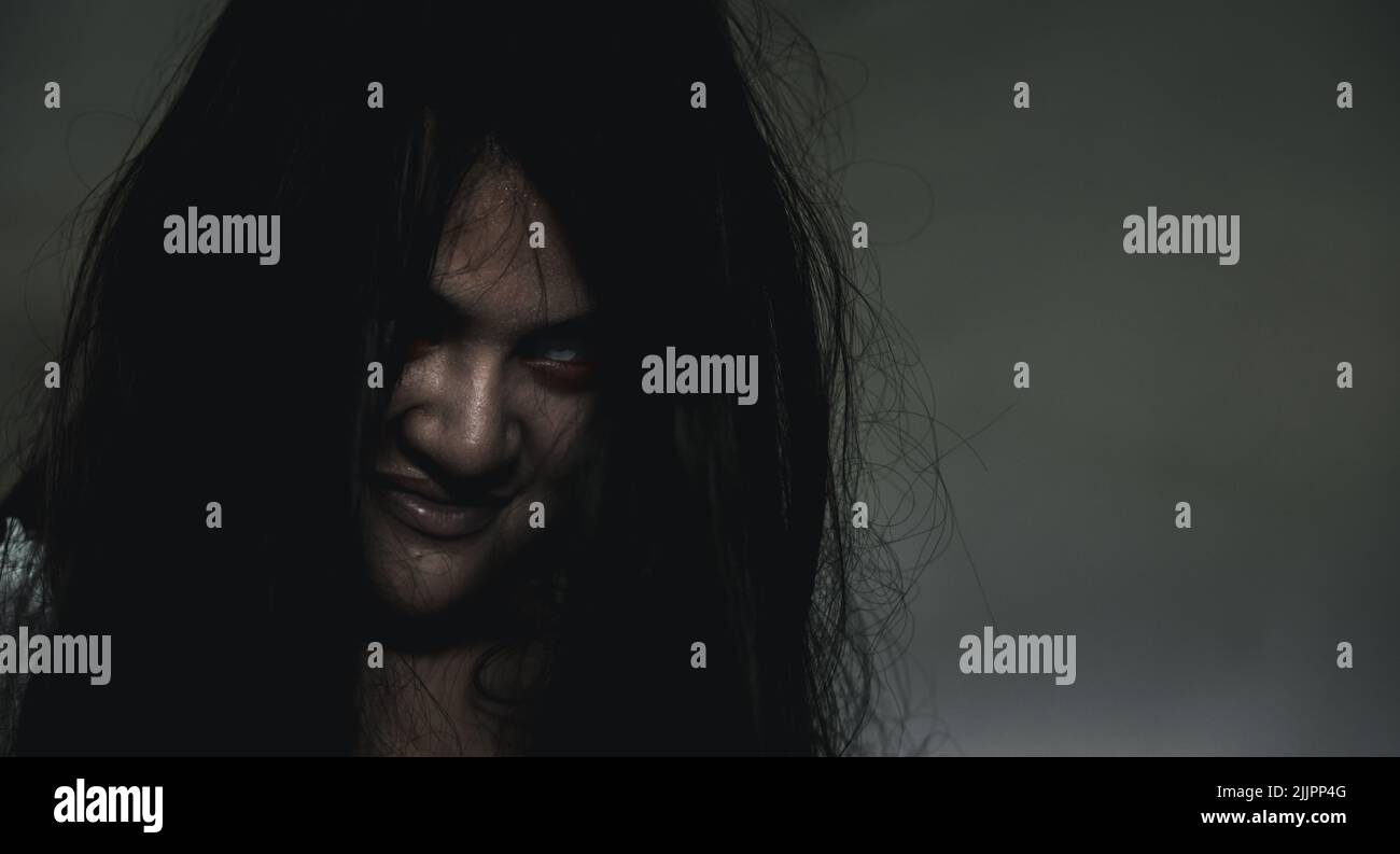 Scary ghost woman. Portrait of Asian ghost or zombie horror creepy scary have hair covering the face her eye at abandoned house dark tone, female make Stock Photo