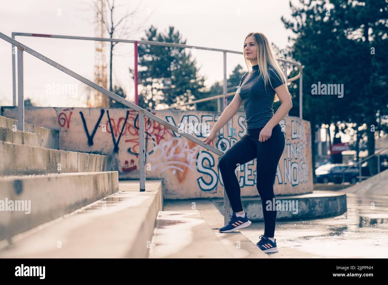 Woman Using Handrail A Caucasian blond female holding handrail and posing on stairs Stock ...