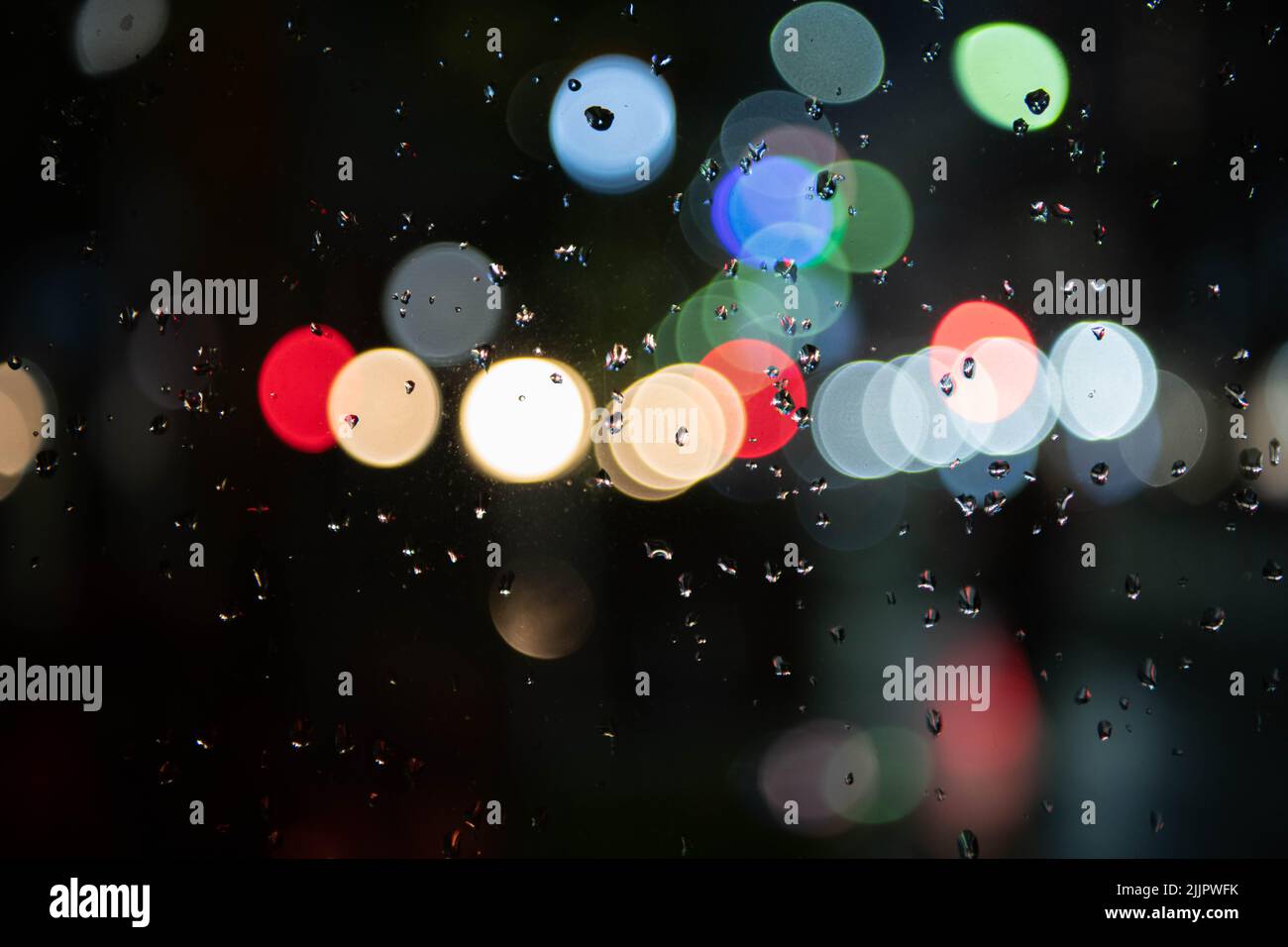 Image of raindrops on the window at night in the city, burry background, abstract bokeh, for background Stock Photo