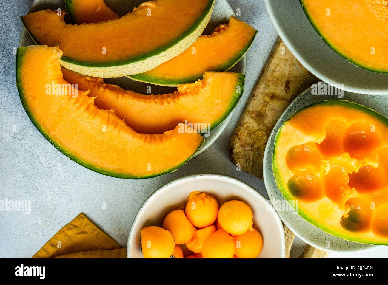 Overhead view of slices of cantaloupe melon and melon balls being prepared on a table Stock Photo