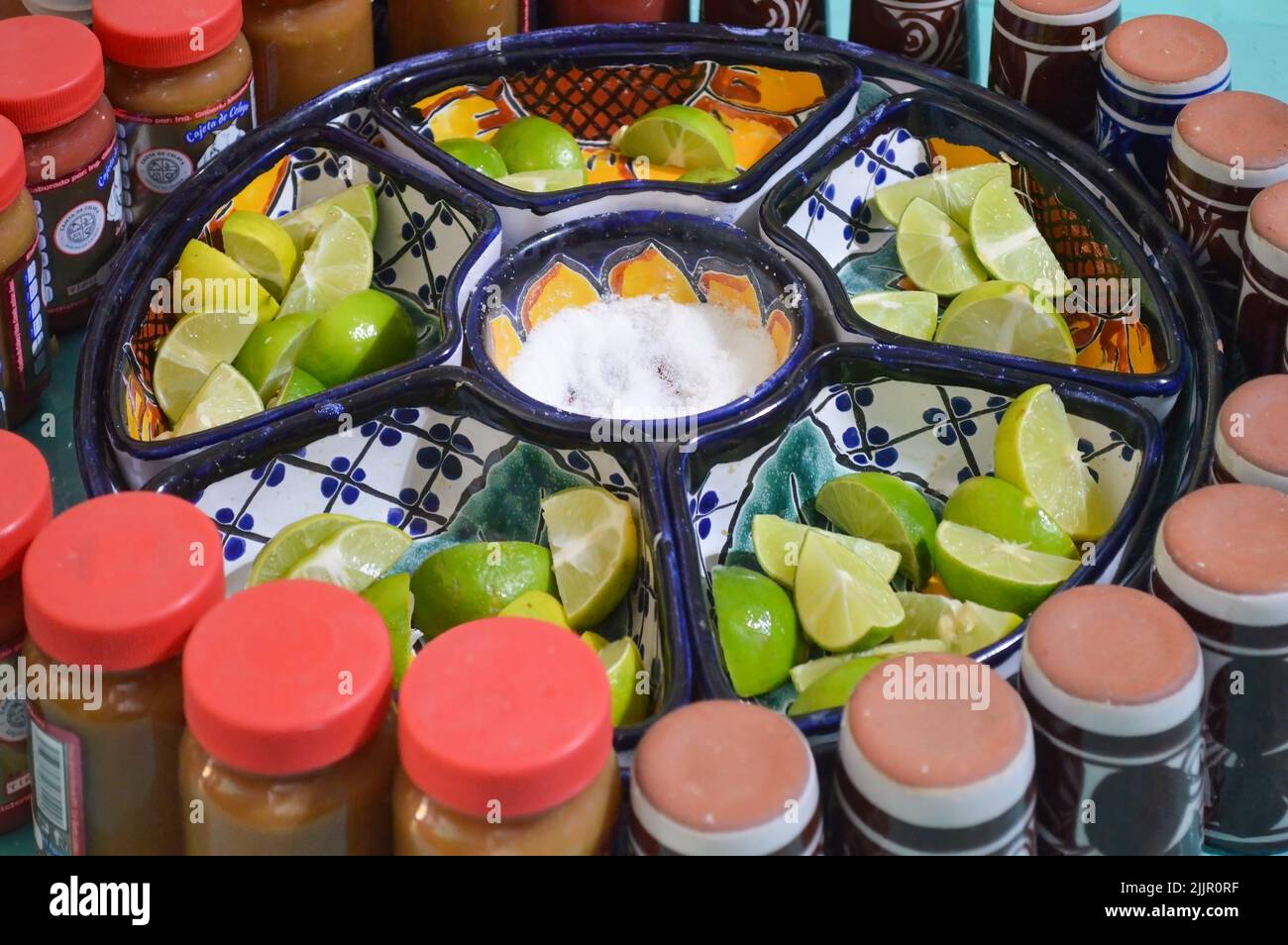 lemon cut in quarters, with salt in the center, with chili powder around, all served in a special earthenware dish Stock Photo