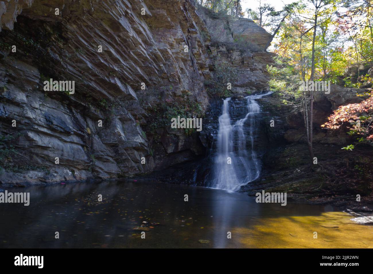 A small water stream and a waterfall flowing down in a rocky place ...