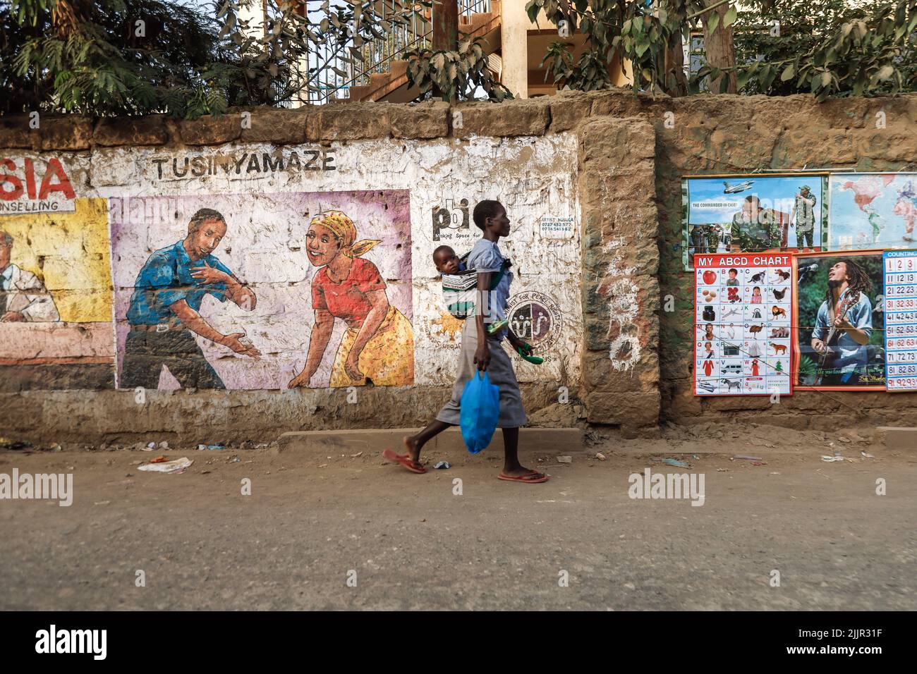 A woman carrying her child walks past a mural painting display of steps ...