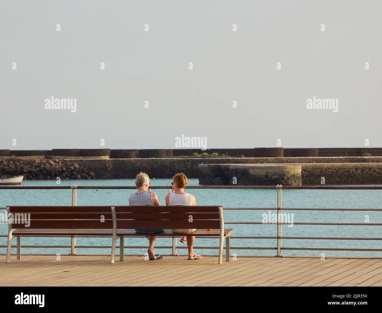 The two women sitting on a bench overlooking the sea Stock Photo - Alamy