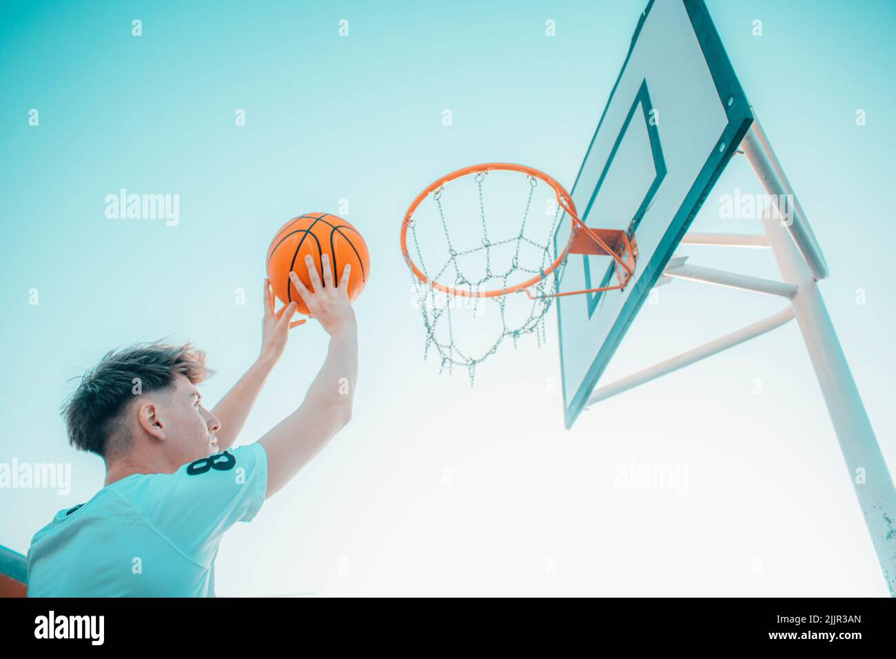 An attractive young Spanish guy throwing a ball in a basketball hoop