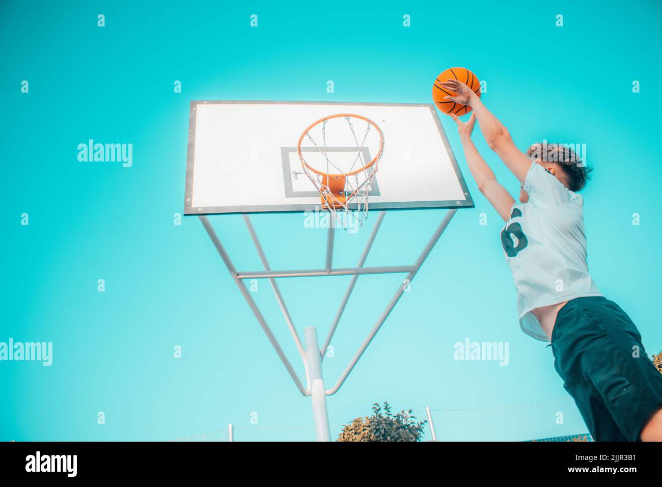 A low angle of a young male dunking a basketball into the hoop Stock Photo