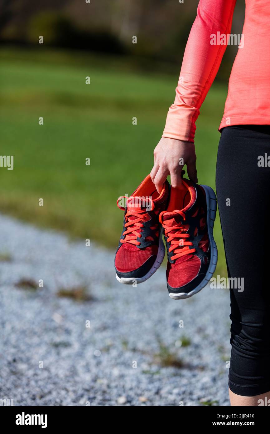 An athlete woman preparing for outdoors training with shoes in her hand, Bavarian National Forest Park, Bavaria, Germany Stock Photo