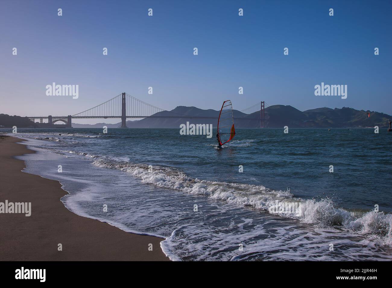 Windsurfer closing in on the beach in front of Golden Gate Bridge, Kite surfer in the distance, San Francisco, California, United States of America Stock Photo