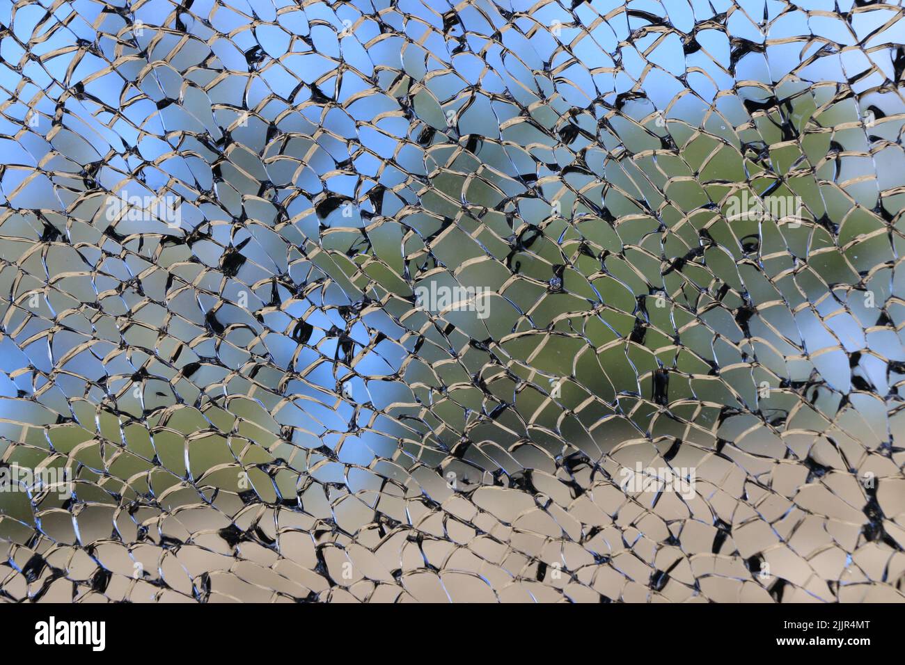 Beautiful black and silver lines of a shattered window create an intricate landscape image. Stock Photo