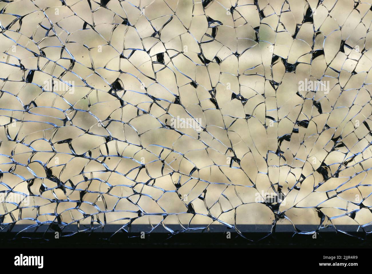 Beautiful black and silver lines of a shattered window create an intricate pattern in the glass. Stock Photo