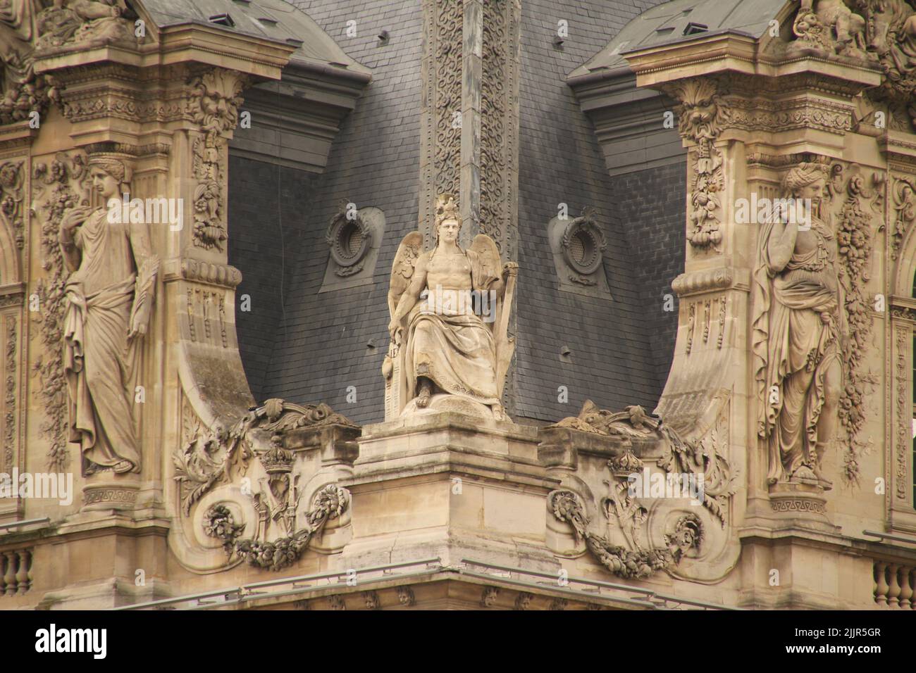 A facade of the Louvre Museum with statues in Paris, France Stock Photo