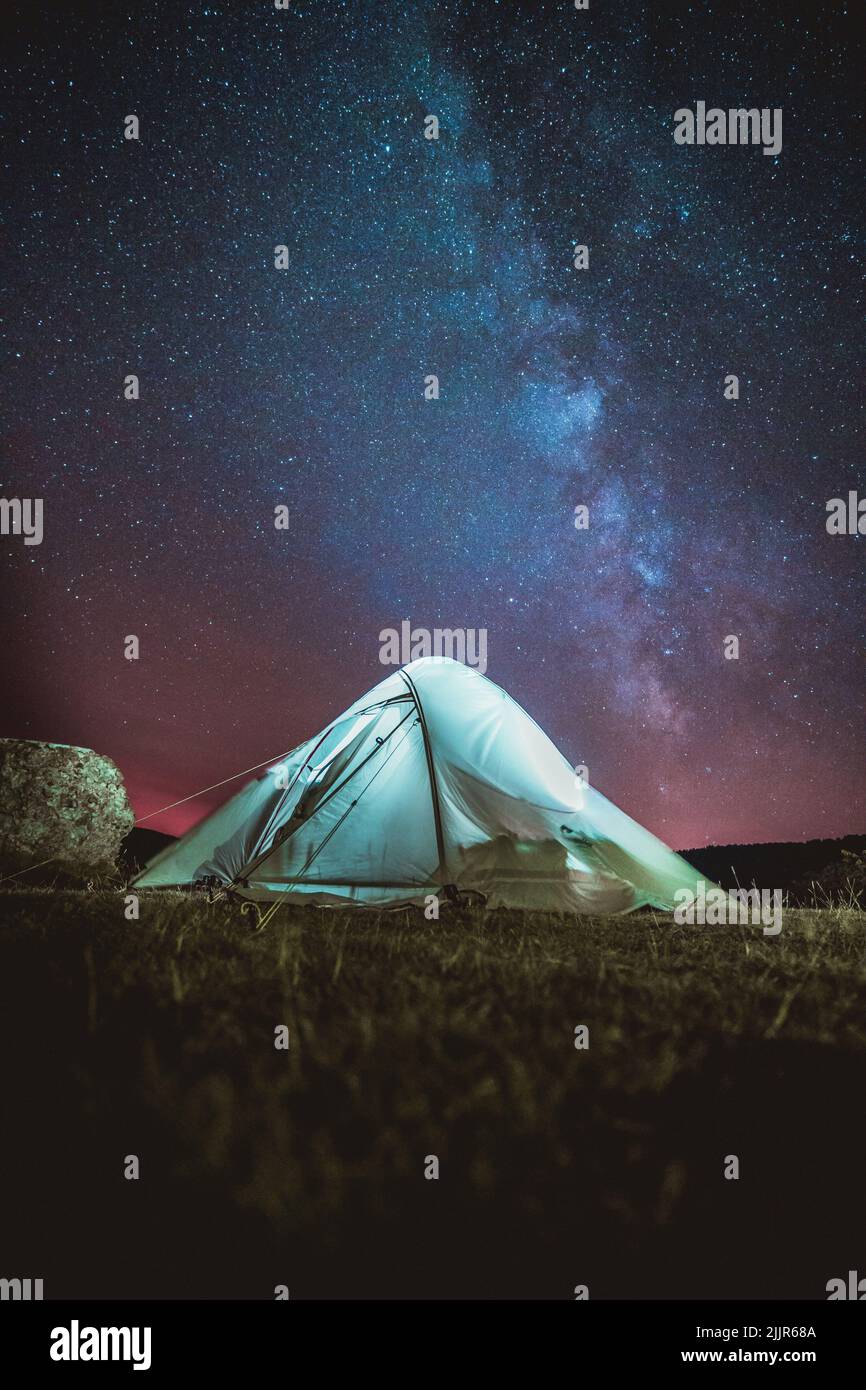 A vertical shot of a tent under the beautiful night sky with Milky Way ...