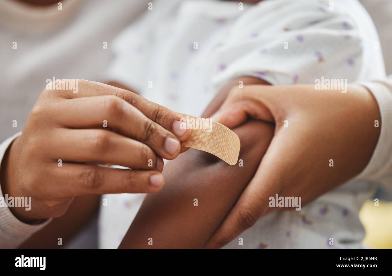 This will make it better. an unrecognizable mother applying a bandaid to her daughters arm at home. Stock Photo