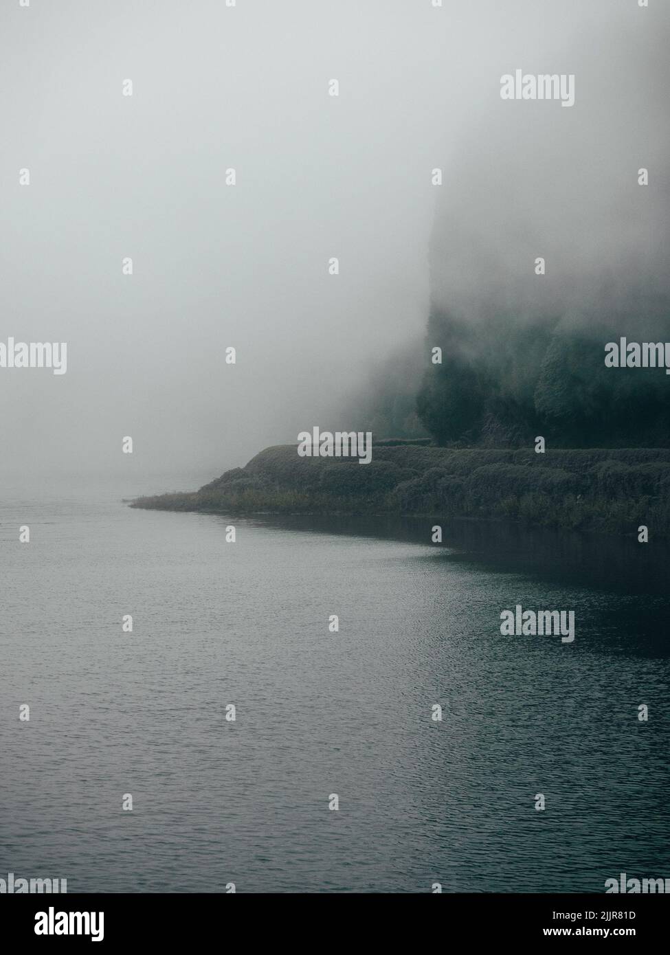 A vertical shot of the ocean and mountainous coast on a foggy day Stock ...