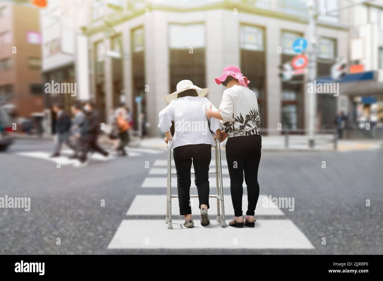 Daughter take care elderly woman walking on street in strong sunlight. Stock Photo