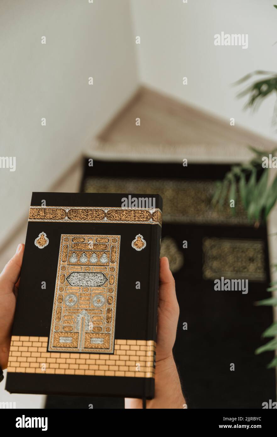 A vertical shot of a black rug and a black velvet Quran decorated with ...