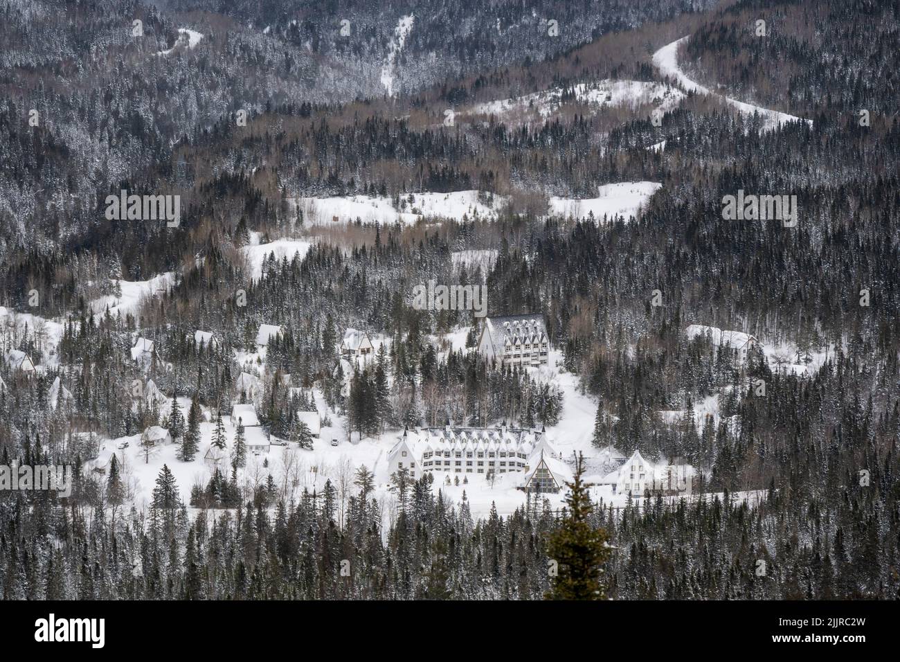 Beautiful background of snowy landscape with trees, clouds and fluffy snow and small town in mountain valley, ski resort concept Stock Photo