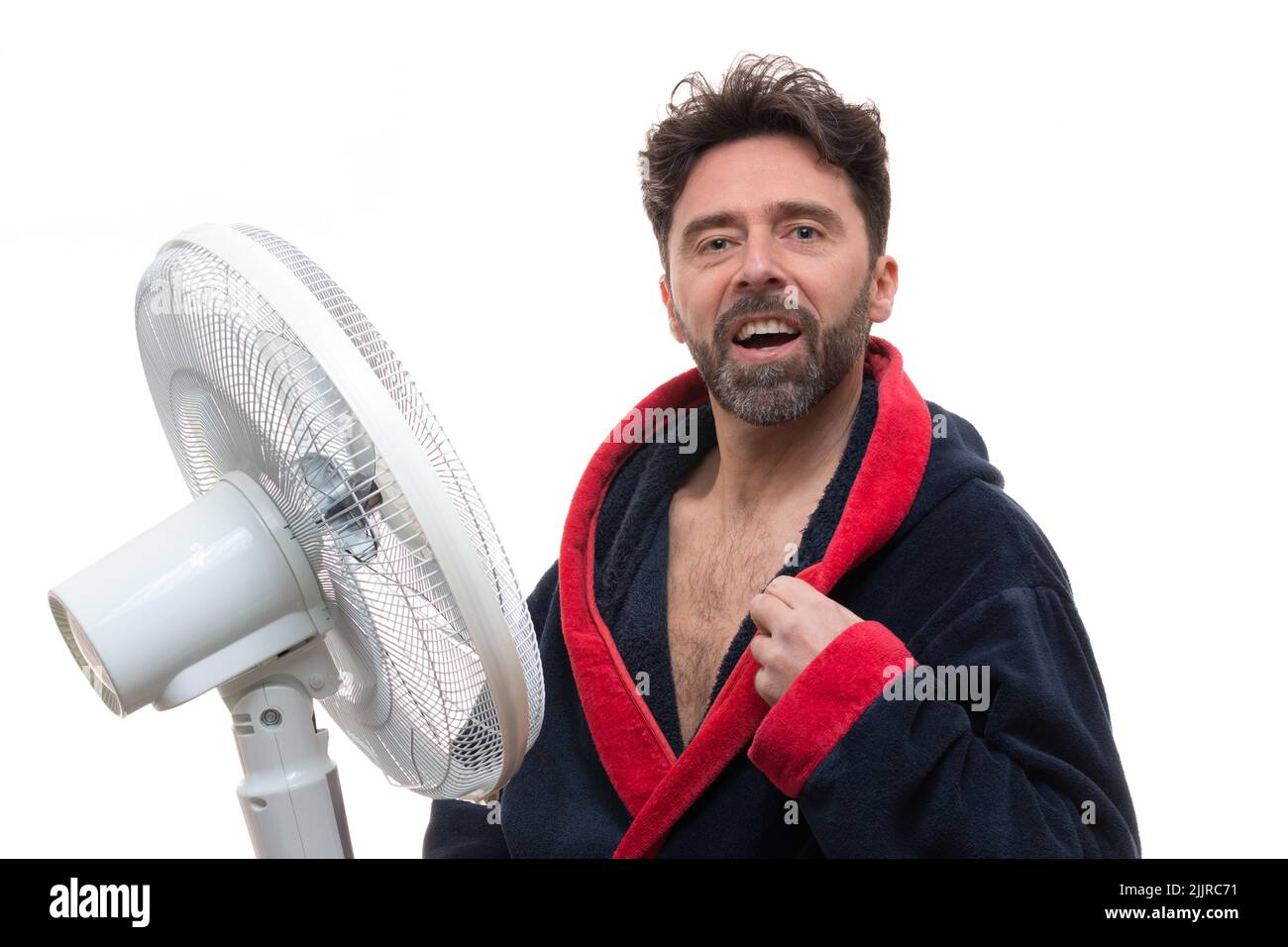 A Caucasian man in bathrobe enjoying the coolness of a fan on a white background Stock Photo