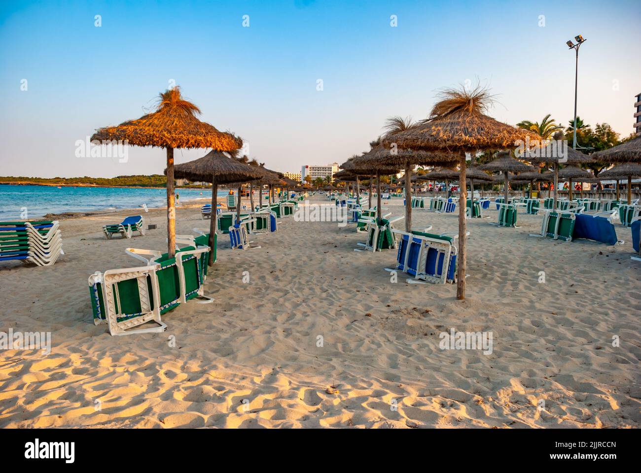 The blue and green sunbeds near thatch parasols on sandy beach in