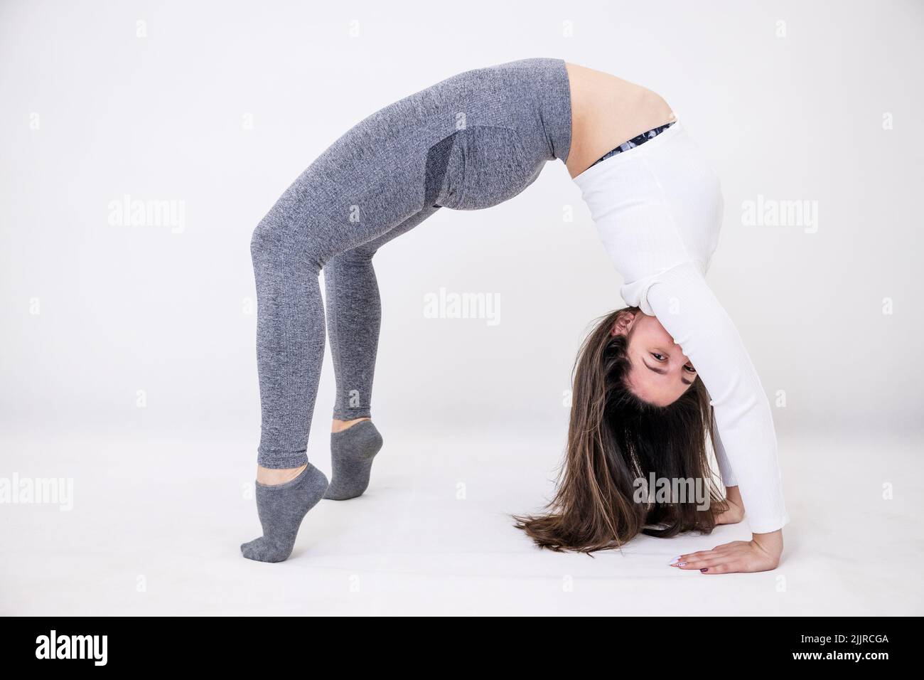 A female yoga teacher doing performing acrobatic movements while exercising Stock Photo