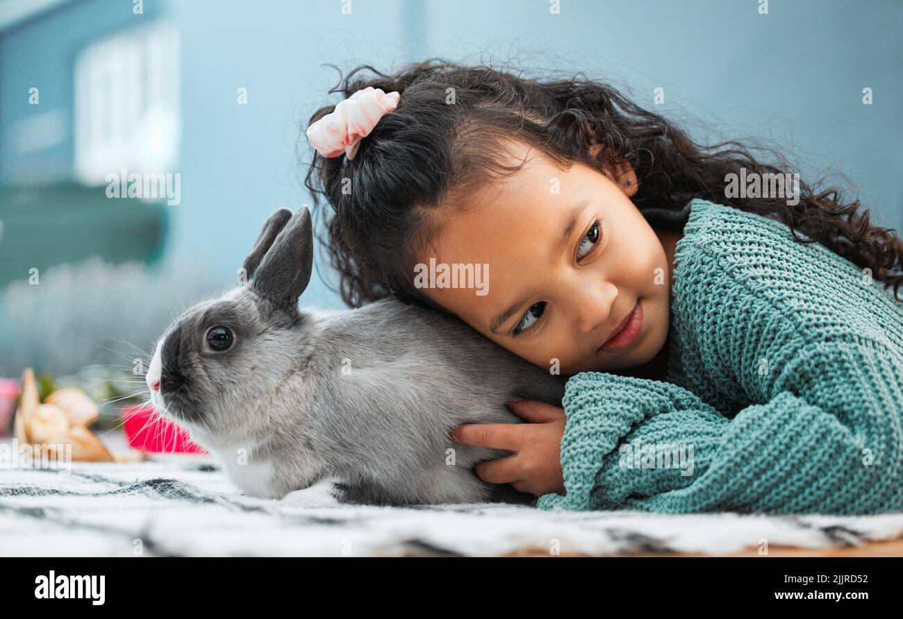 I love spending my days at home with my rabbit. an adorable little girl bonding with her pet rabbit at home. Stock Photo