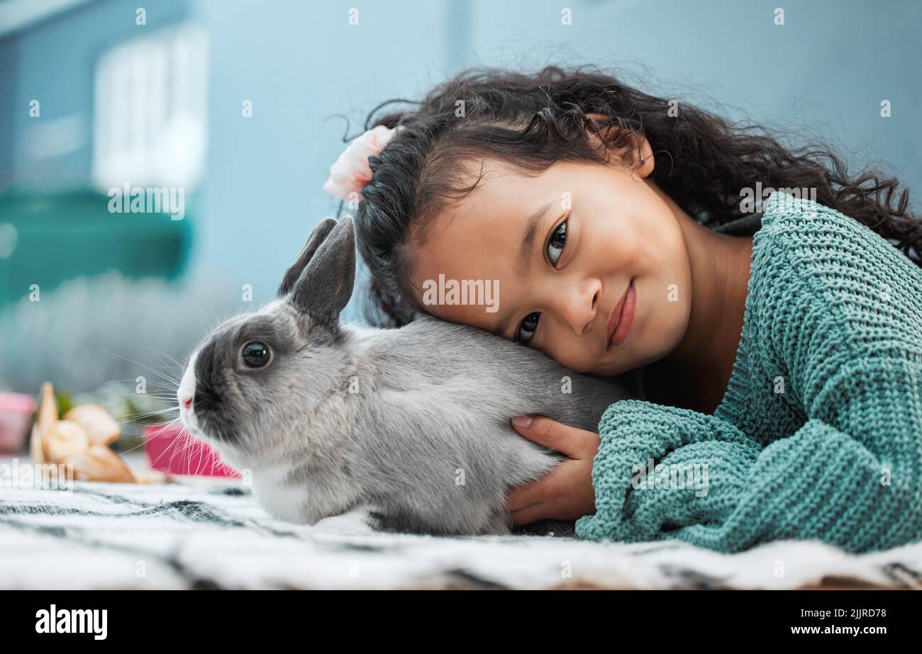 My pet rabbit loves hugs. an adorable little girl bonding with her pet rabbit at home. Stock Photo