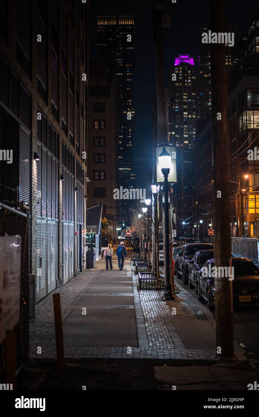 The two people walking down an empty street at night Stock Photo