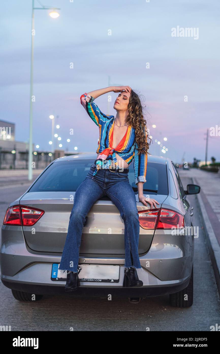 A vertical shot of beautiful girl sitting in the back of the car Stock Photo