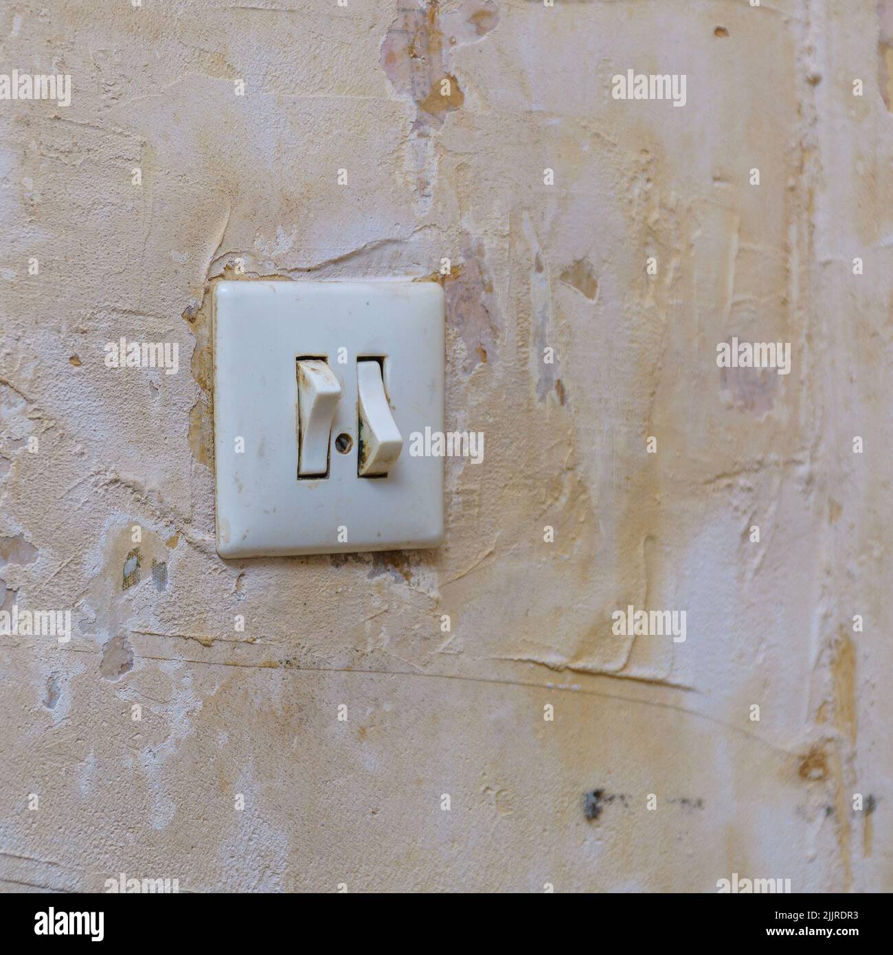 Old light switch on a shabby battered wall. Selective focus Stock Photo