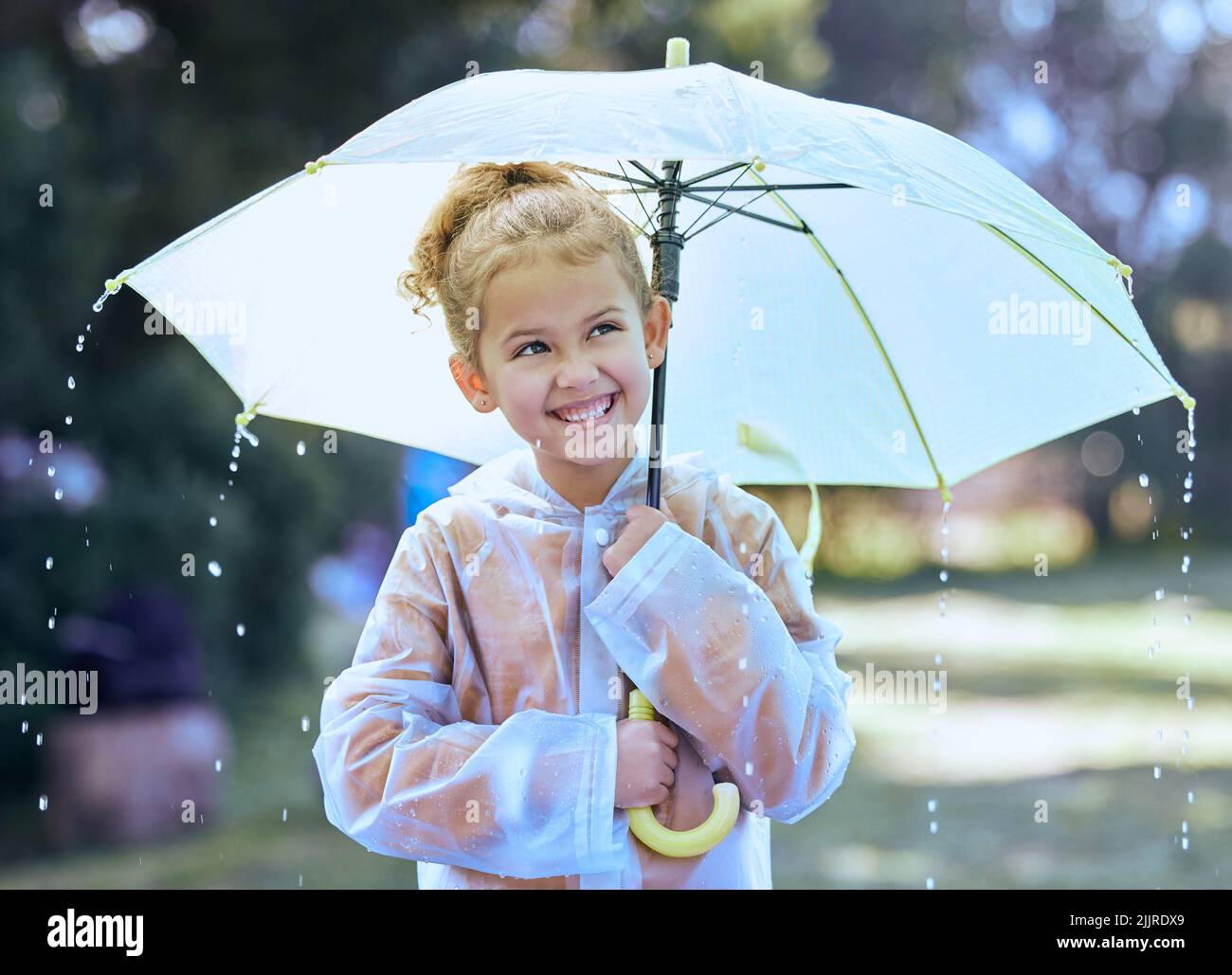 Rainy days are the best. a little girl playfully standing in the rain