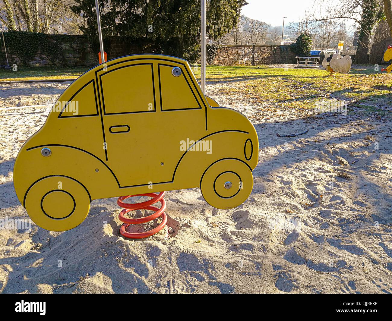 A closeup shot of a spring seesaw in shape of a car in the playground with sandy ground Stock Photo
