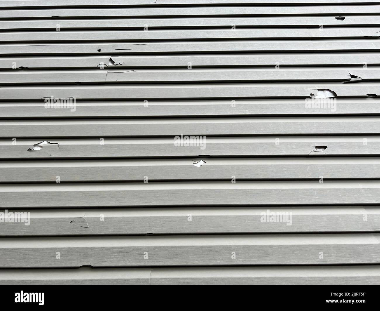 Holes in the exterior siding of the home from hail storm damage. The