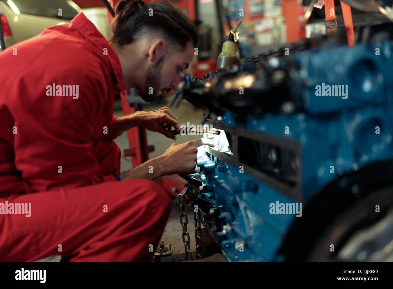 A young Caucasian mechanic mounting the car engine Stock Photo