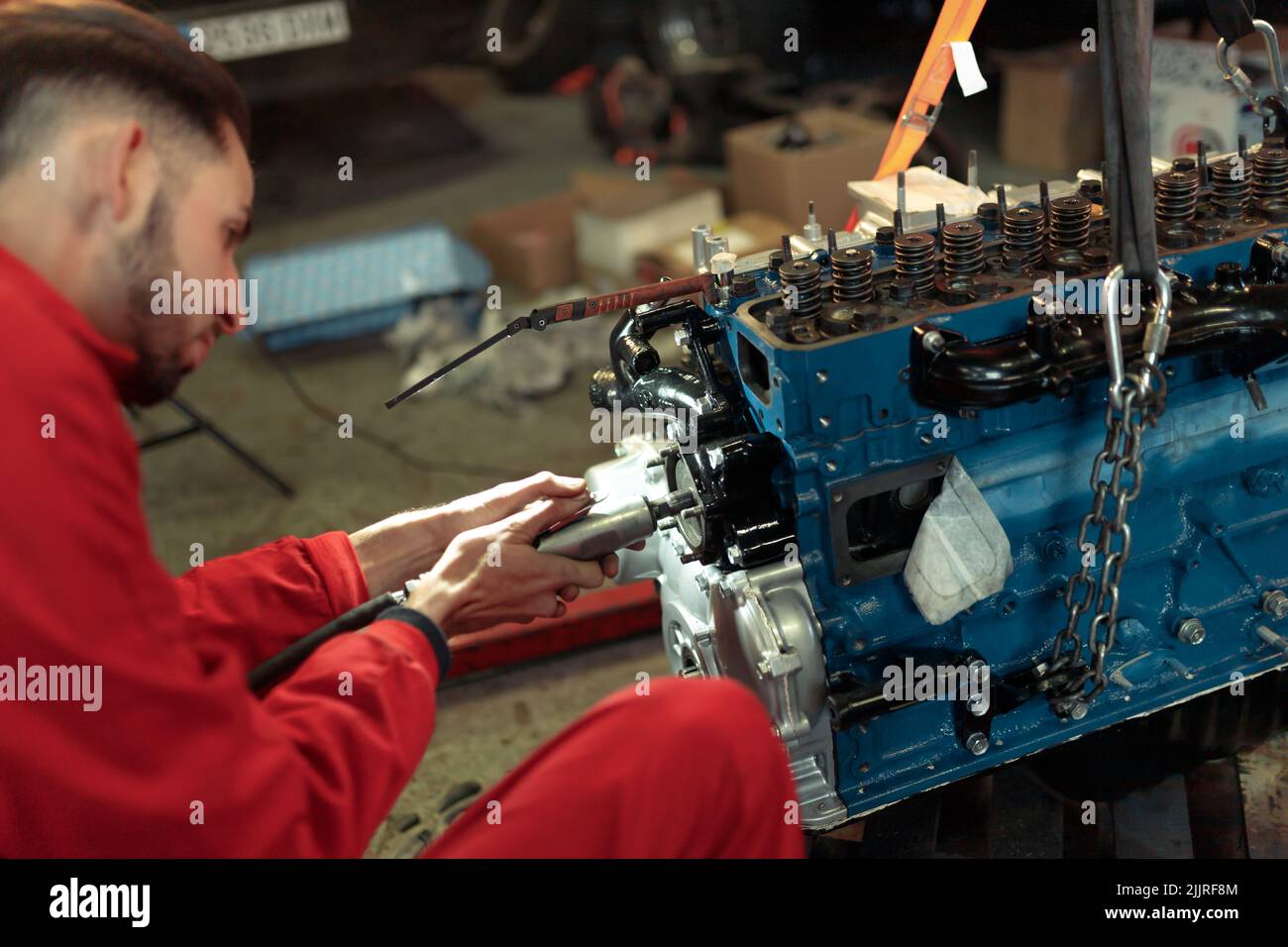 A young Caucasian mechanic mounting the car engine Stock Photo