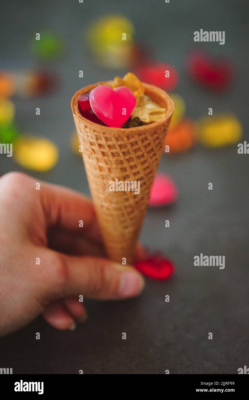 A vertical closeup shot of an ice cream cone filled with gummy bears and jellies Stock Photo