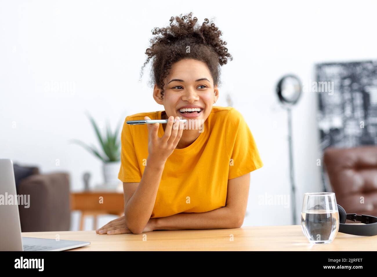 Young African american woman sending voice message through using mobile phone smiling friendly Stock Photo