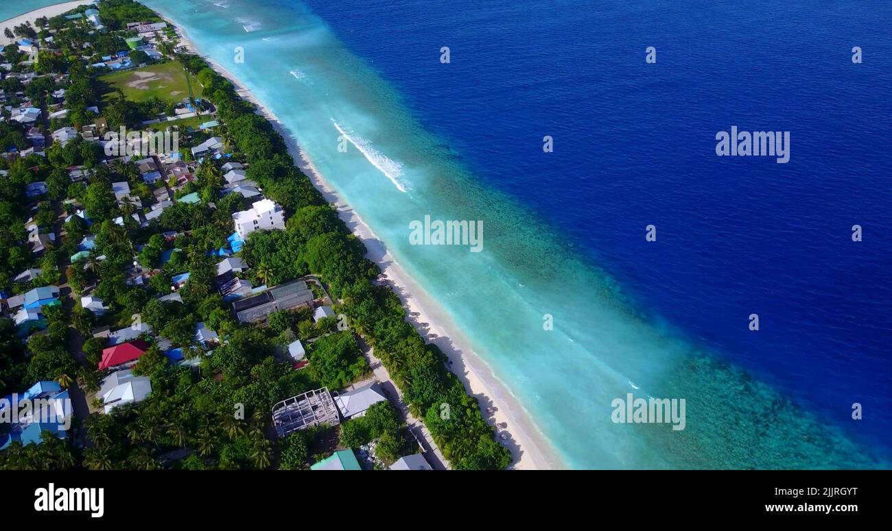 An aerial top view of houses surrounded with trees on the sandy beach ...