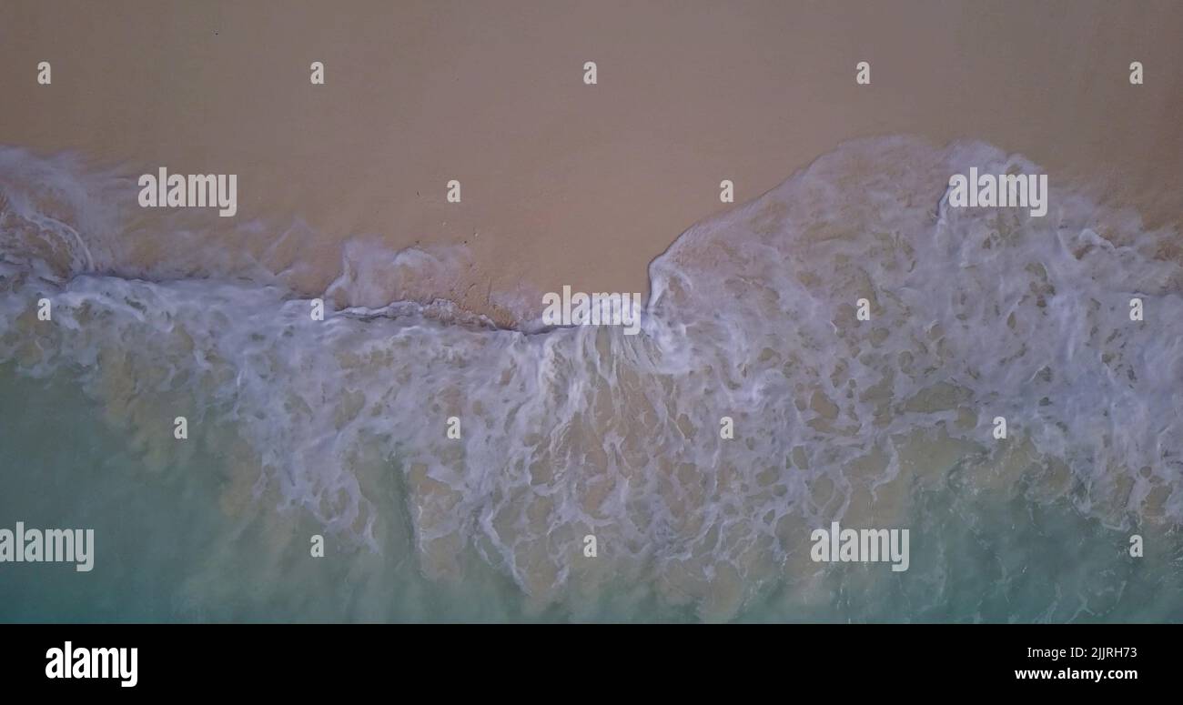An aerial view of soft ocean waves with foam on a sandy beach Stock ...