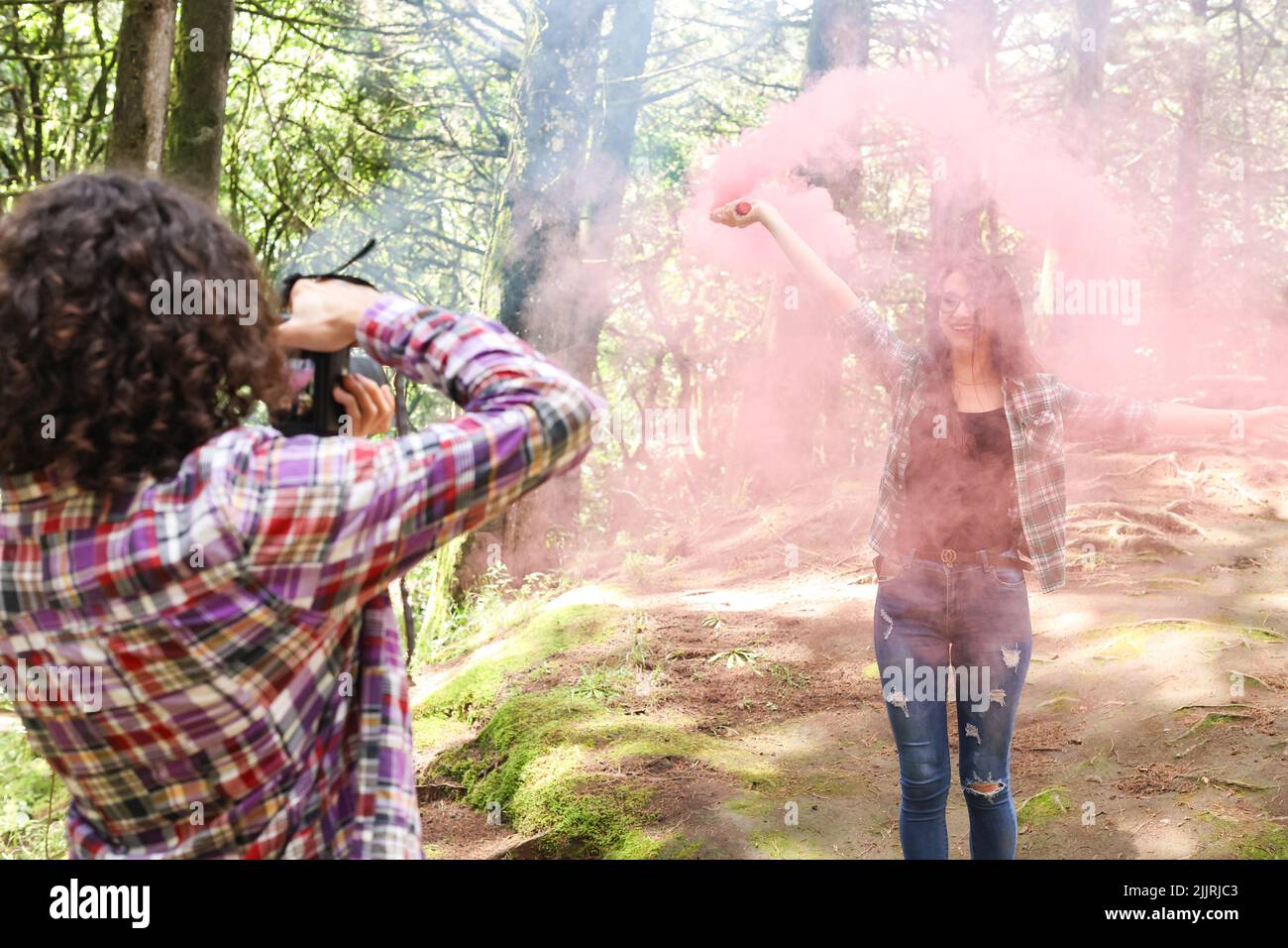 Anonymous profesional Photographer taking photographs of model in the forest holding a red smoke bomb at Costa Rica Stock Photo