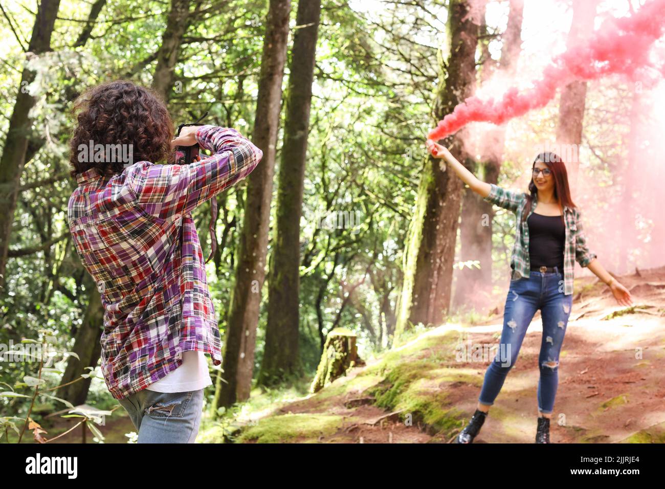 Anonymous profesional Photographer taking photographs of model in the forest holding a red smoke bomb at Costa Rica Stock Photo