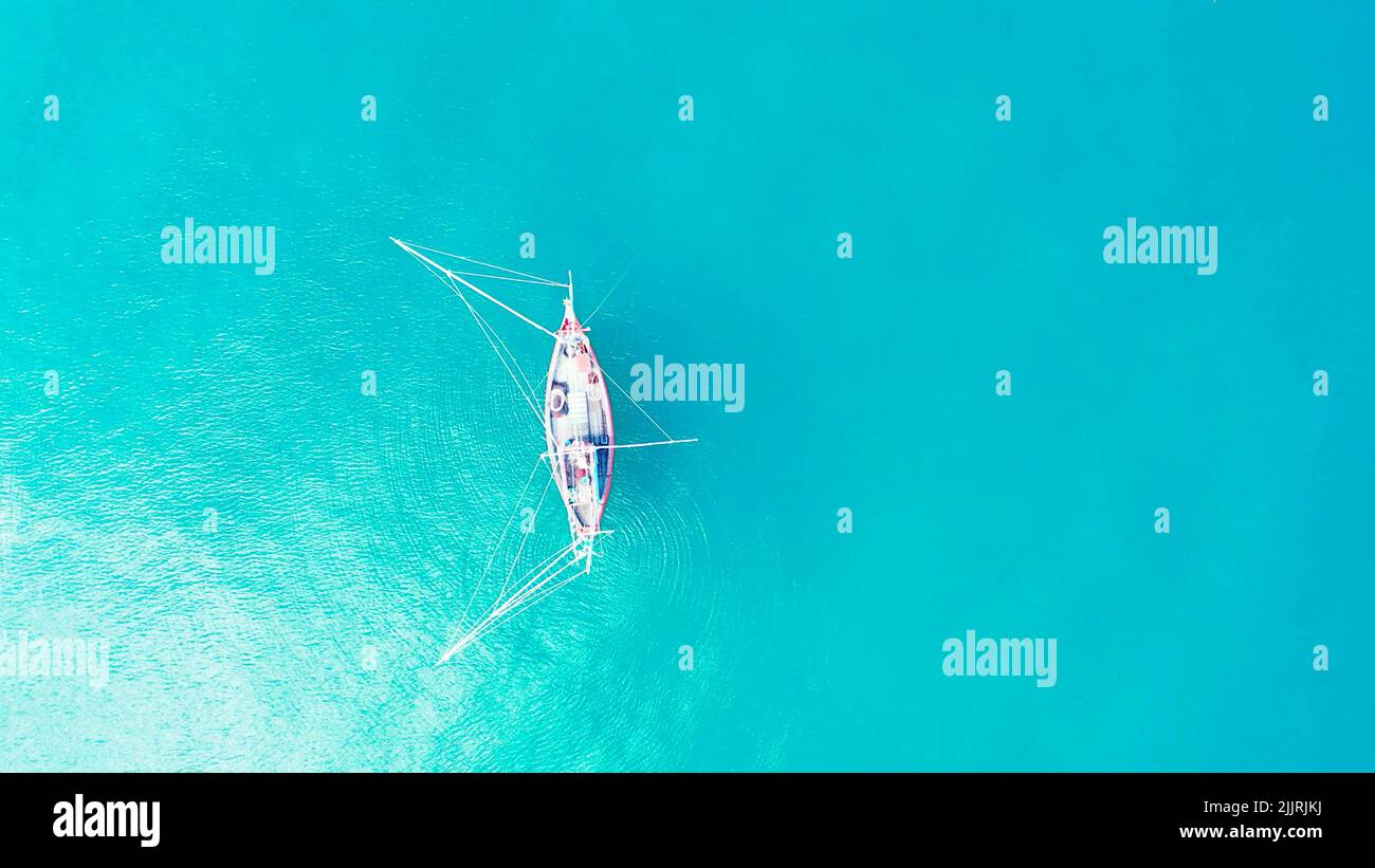 An aerial view of a ship sailing in the turquoise water in Maldives ...